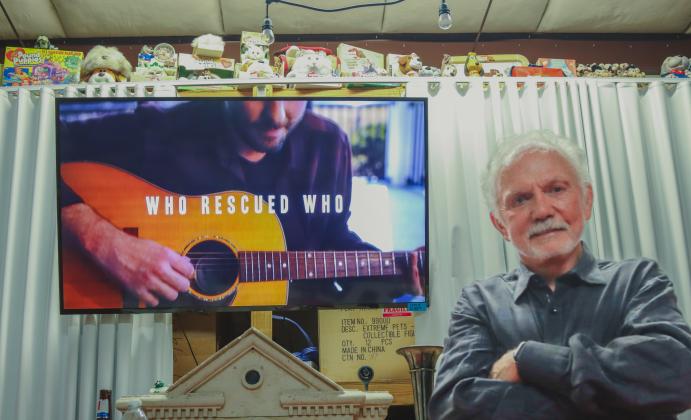 Mike Bowling plays the music video for “Who Rescued Who” at Mike Bowling Enterprises Inc. in Fernandina Beach. Photo by Ashley Chandler/News-Leader