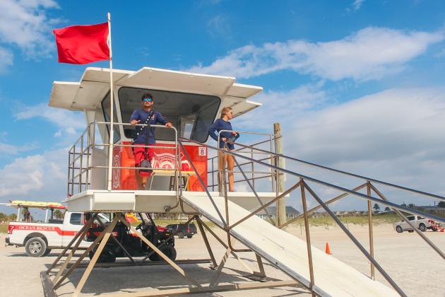 Fernandina Beach lifeguards Adalai Kwiatkowski and Evan Main stand next to the red flag signaling hazardous ocean conditions on Tuesday.