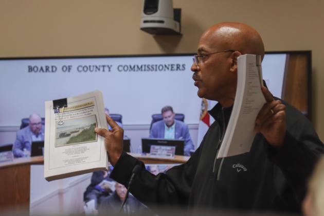 President of Save Historic American Beach Inc. Mark Dawkins holds up the two protected species management plans from Valusia and St Johns counties at the Aug. 11 Board of County Commissioners meeting.. Photo by Ashley Chandler/News-Leader