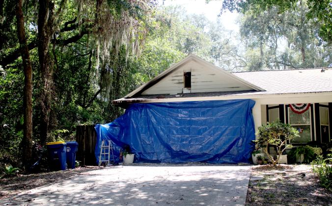 Above, The Heritage family home is covered by a tarp Wednesday on the side of the house that was most damaged after a lightning strike started a fire in the attic Tuesday. Photo by Marisa DeMar/News-Leader