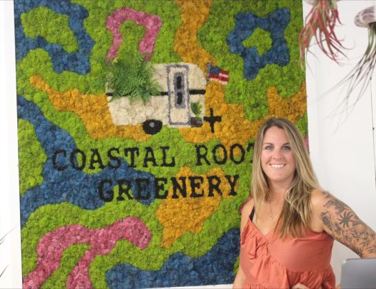 Ashley Burnett poses in front of moss art piece at Coastal Roots Greenery on Friday. Marisa DeMar/News-Leader