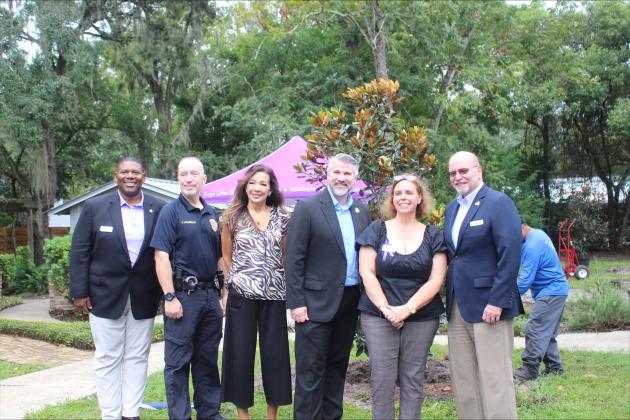 County and city representatives pose in front of the two trees with the executive director of Micah’s Place, Tracie Fasel. 
