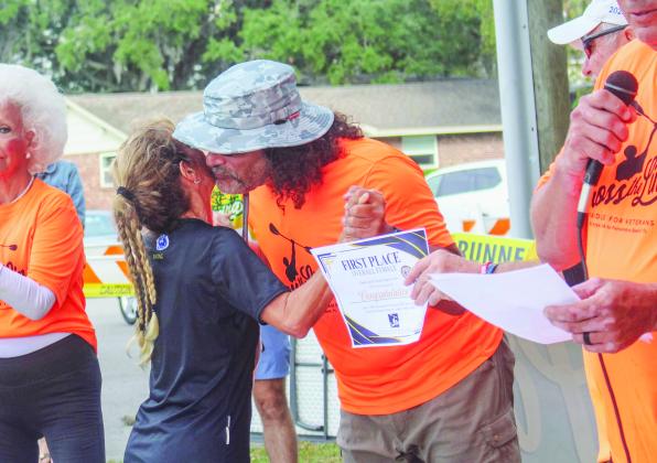 Women's first-place winner Brinda Linck shares a hug with Cross the Line co-founder Paul Lore as he presents her award after the race.