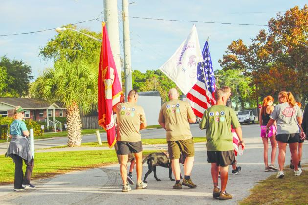 Steven Stanevich, Ivan Stanevich, Webb Skelton, Nolan Maccabee, and dog "socks" prepare for the 5K with a large American Flag and U.S Marine Corps flag.