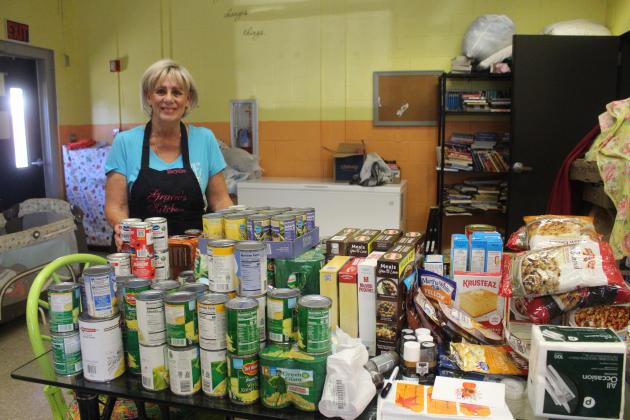 Maryellen Crocker stands in front of the food donated to be part of the Thanksgiving boxes that Gracie’s Kitchen will be distributing for the holiday. 