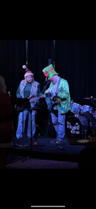 A festive husband-and-wife duo perform at open mic night at Inkwell Art Bar.