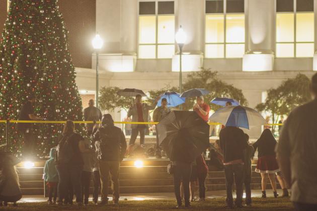 Attendees of the Nassau County tree lighting event Friday watch the fireworks that followed the lighting from under umbrellas at the Robert M. Foster Justice Center in Yulee. Photo by Ashley Chandler/News-Leader