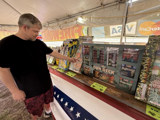 Brian Carlton points to merchandise at the Southern Fireworks tent in Fernandina Beach.