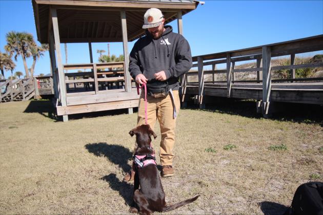 Andrew Ensign of Sentinel K9 Academy holds Daisy, the 4-month-old Labrador retriever he is training to be an autism assistance dog, at Main Beach on Dec 31. 