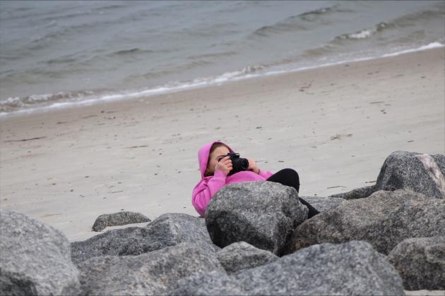Francine (Frankie) Gross lays on the sand to capture the perfect shot of the fort on Saturday.  By Marisa DeMar/News-Leader