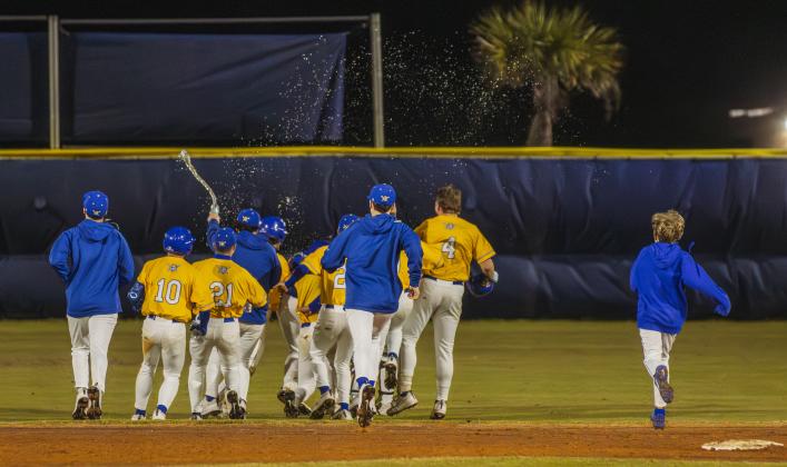 The Pirates swarm No. 8 Trace Farmer after he hit the game-winning RBI in Friday’s game against Baldwin. Photo by Ashley Chandler/News-Leader