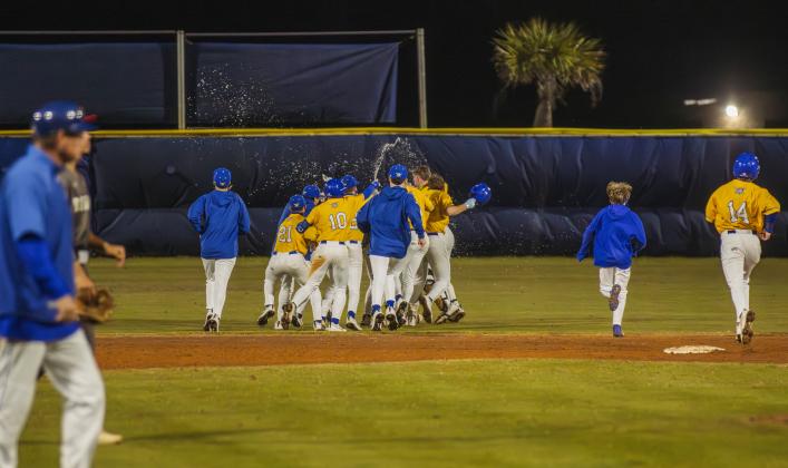 The Pirates swarm No. 8 Trace Farmer after he hit the game-winning RBI in Friday’s game against Baldwin. Photo by Ashley Chandler/News-Leader