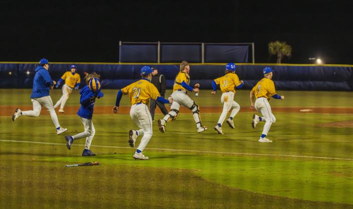 The Pirates swarm No. 8 Trace Farmer after he hit the game-winning RBI in Friday’s game against Baldwin. Photo by Ashley Chandler/News-Leader