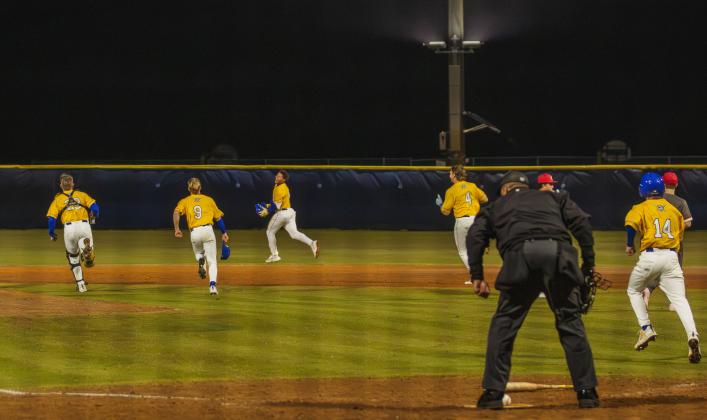 The Pirates swarm No. 8 Trace Farmer after he hit the game-winning RBI in Friday’s game against Baldwin. Photo by Ashley Chandler/News-Leader