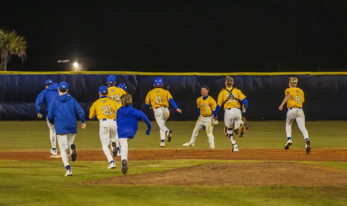 The Pirates swarm No. 8 Trace Farmer after he hit the game-winning RBI in Friday’s game against Baldwin. Photo by Ashley Chandler/News-Leader