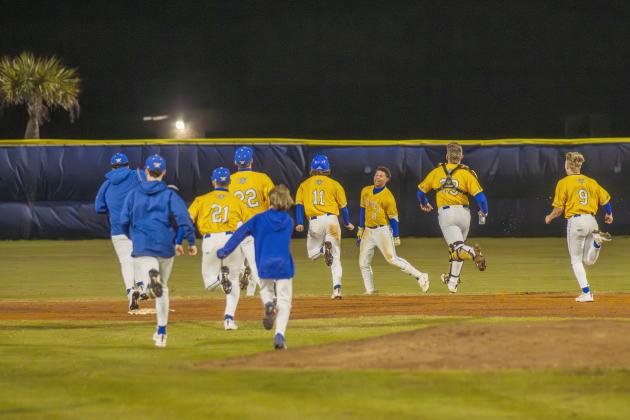 The Pirates swarm No. 8 Trace Farmer after he hit the game-winning RBI in Friday’s game against Baldwin. Photo by Ashley Chandler/News-Leader