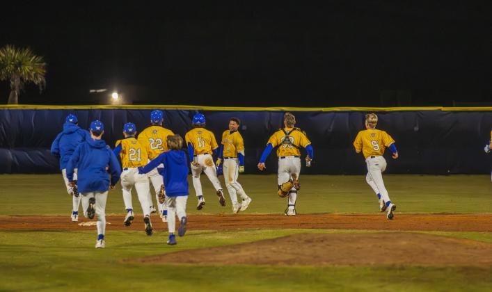 The Pirates swarm No. 8 Trace Farmer after he hit the game-winning RBI in Friday’s game against Baldwin. Photo by Ashley Chandler/News-Leader