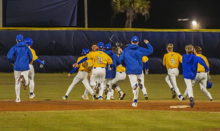 The Pirates swarm No. 8 Trace Farmer after he hit the game-winning RBI in Friday’s game against Baldwin. Photo by Ashley Chandler/News-Leader
