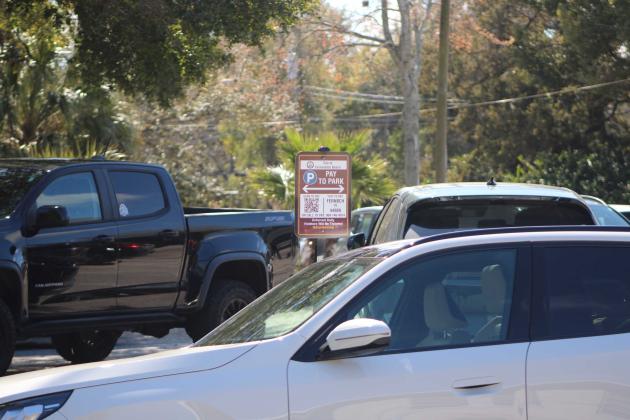A car is parked in front of paid parking signage containing the QR code with directions to pay Monday afternoon in downtown Fernandina Beach. Marisa DeMar/News-Leader