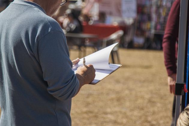 A local signs a recall petition in February at the Fernandina Beach Farmers Market - Mid-week Market. Photo by Ashley Chandler/News-Leader