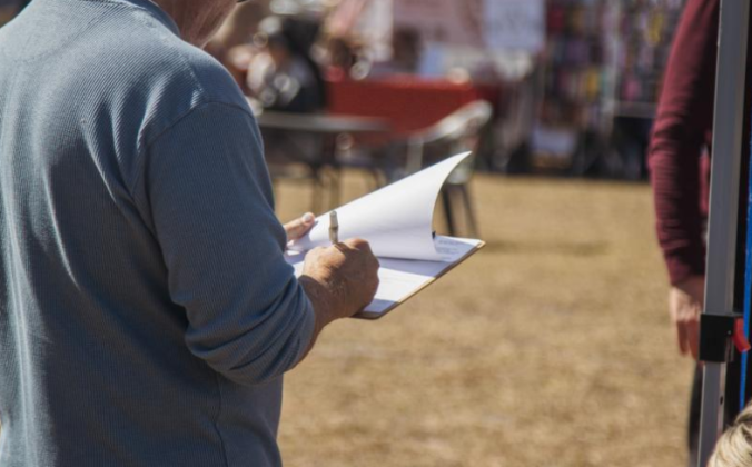 A local signs a recall petition in February at the Fernandina Beach Farmers Market - Mid-week Market. Photo by Ashley Chandler/News-Leader