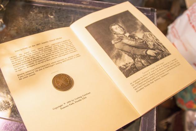 A MacGregor Medallion sits atop a book by Carling Gresham that tells the history of the medals.