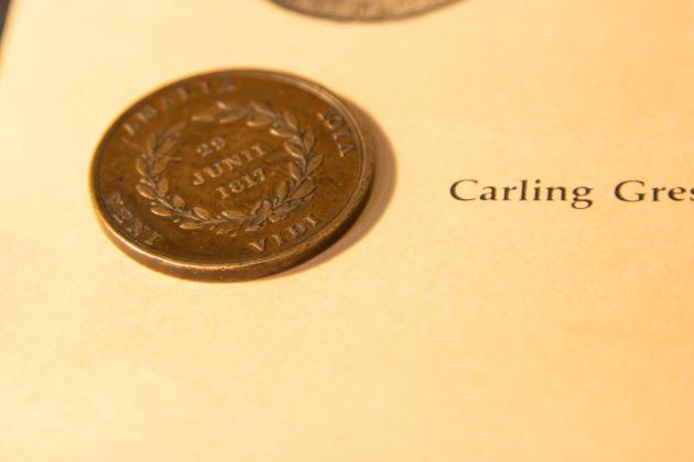 A MacGregor Medallion sits atop a book by Carling Gresham that tells the history of the medals.
