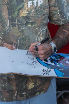 Ecuadorian mixed martial artist, Marlon “Chito” Vera signs a skateboard at Main Beach Park during the Gumball 3000. Photo by Ashley Chandler/News-Leader