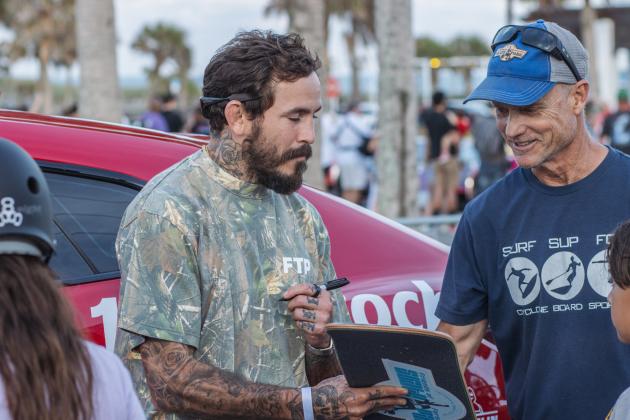 Ecuadorian mixed martial artist, Marlon “Chito” Vera signs a skateboard for Mike Nichols, Treasurer of Friends of Fernandina Skatepark at Main Beach Park during the Gumball 3000
