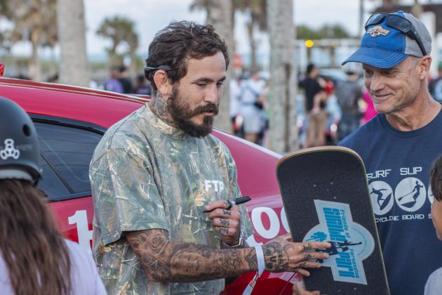 Ecuadorian mixed martial artist, Marlon “Chito” Vera signs a skateboard for Mike Nichols, Treasurer of Friends of Fernandina Skatepark at Main Beach Park during the Gumball 3000