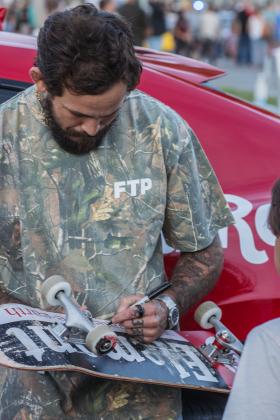 Ecuadorian mixed martial artist, Marlon “Chito” Vera signs a skateboard at Main Beach Park during the Gumball 3000. Photo by Ashley Chandler/News-Leader