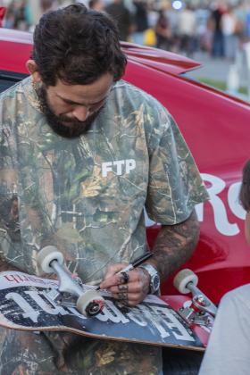 Ecuadorian mixed martial artist, Marlon “Chito” Vera signs a skateboard at Main Beach Park during the Gumball 3000