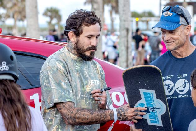 Ecuadorian mixed martial artist, Marlon “Chito” Vera signs a skateboard for Mike Nichols, Treasurer of Friends of Fernandina Skatepark at Main Beach Park during the Gumball 3000. Photo by Ashley Chandler/News-Leader