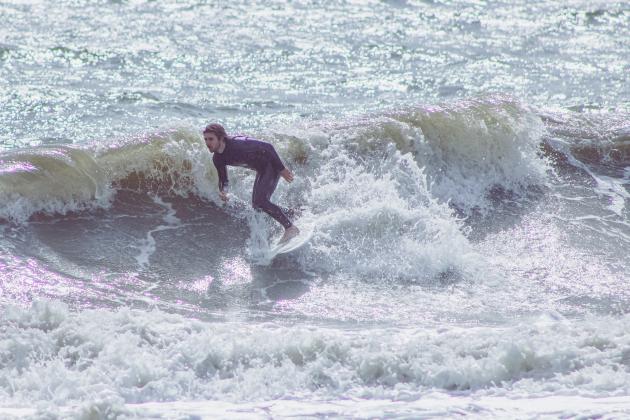 A surfer catches a wave earlier this year at Main Beach. Marisa DeMar/News-Leader