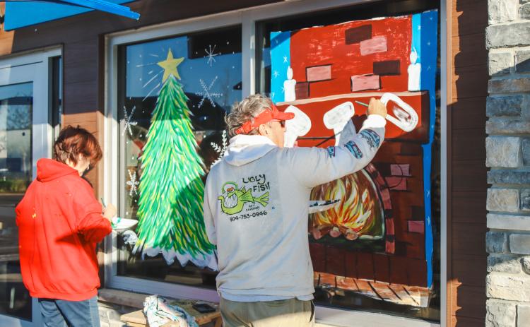 Lamar Miles of Ugly Fish Art Company, right, paints the windows at Culver’s with the help of Robyn Mejia. Photo by Ashley Chandler/News-Leader