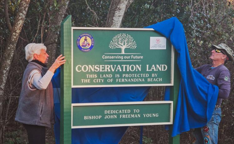 Fernandina Beach Conservation and Environmental Manager Kathy Russell and Jack Imber remove the cover from the Conservation Land sign, dedicating the city’s land on North 11th Street to Bishop John Freeman Young. Photos by Ashley Chandler/News-Leader