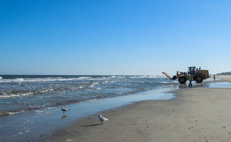 Workers clean dredging equipment Monday at Main Beach. Photo by Ashley Chandler/News-Leader