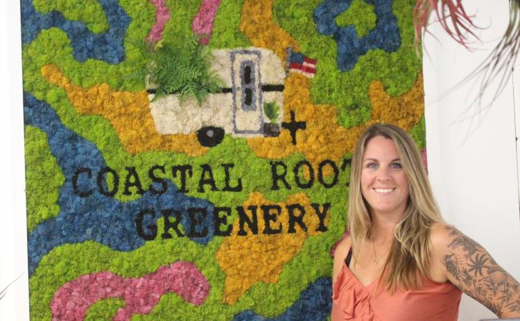 Ashley Burnett poses in front of moss art piece at Coastal Roots Greenery on Friday. Marisa DeMar/News-Leader