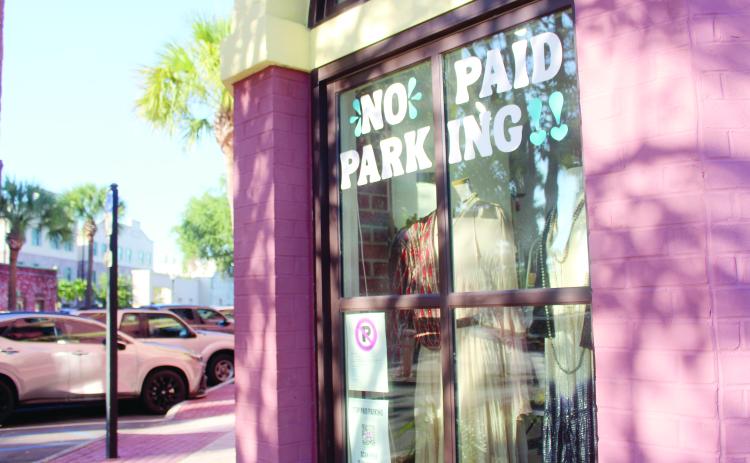 Marisa DeMar/News-Leader  A No Paid Parking sign and QR code to the citizen petition placed on the corner of a shop window in downtown Fernandina Beach on Tuesday.