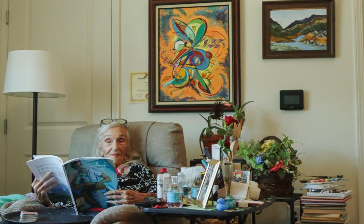 Dee Dee Bartels flips through one of the books she authored during her long life in her apartment in Fernandina Beach in April 2025. Photo by Ashley Chandler/News-Leader