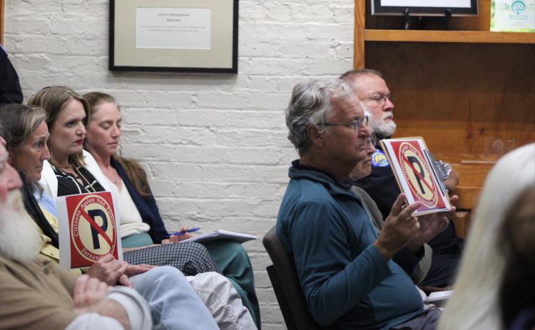 Meeting attendees hold anti-paid parking signs in their seats at Tuesday's meeting. By Marisa DeMar/News-Leader