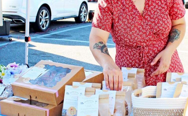 Cutline 1: Molly Vogel organizes sourdough breads and treats at her Doris & Eris Artisan Bakery stand at the Markets by Mariah farmers market at Tractor Supply on Saturday.