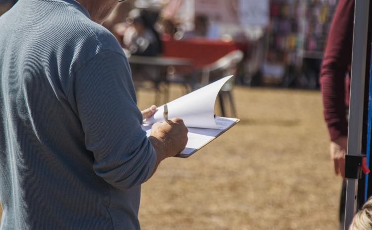 A local signs a recall petition in February at the Fernandina Beach Farmers Market - Mid-week Market. Photo by Ashley Chandler/News-Leader