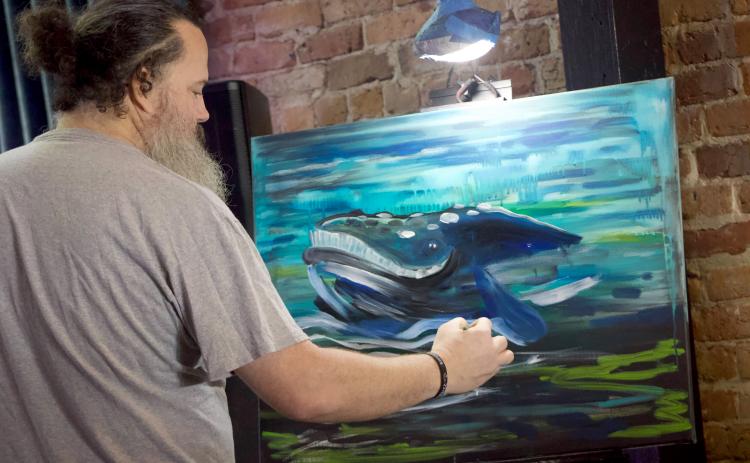 Brian Barnard paints a whale for the raffle during the Whale Baby Shower hosted by the Amelia Island Whale Ambassadors on Wednesday. Photo Marisa DeMar/News-Leader