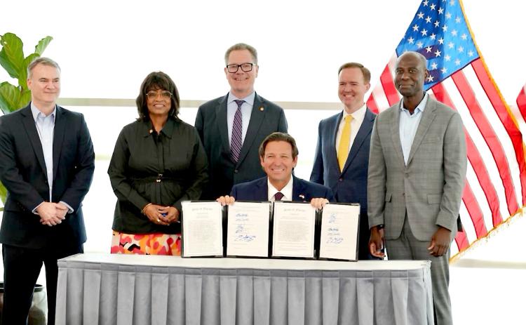 Gov. Ron DeSantis shows two bills he signed on Wednesday in Jacksonville. Photo provided by News Service of Florida