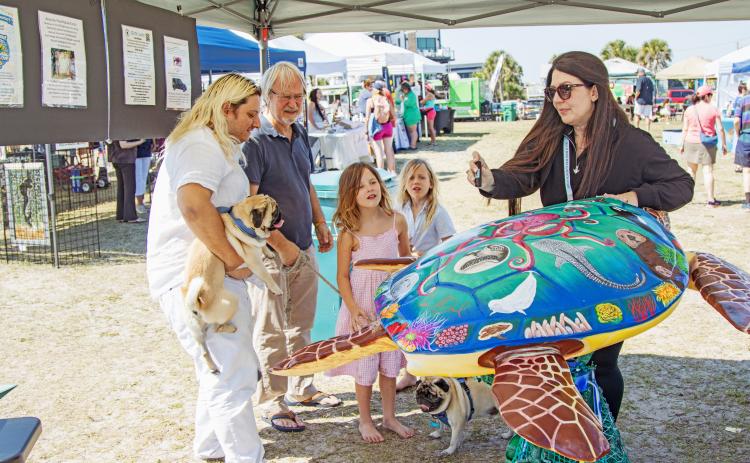 Artist Tina McDaniel shows off her art work "Scout" to education children on plastic pollution at the Sea Turtle Festival. Photo by Ashley Chandler/News-Leader