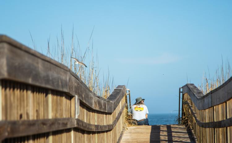 A man sits on a beach walkover at Main Beach earlier this year. The city is working with Kimley-Horn and associates, Inc. on a Parks Master Plan. Staff is focused on the needs for beach accesses and walkovers, and other recreation needs. Photo by Ashley Chandler/News-Leader