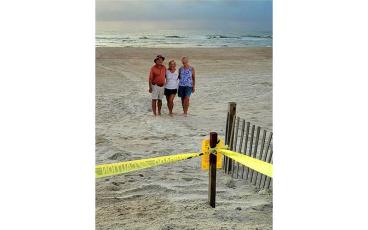 Micki Marvin and her parents pose in front of the green sea turtle nest they found, the 15th this season. Submitted photo