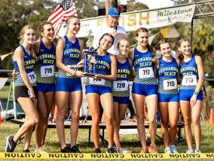 The Fernandina Beach High School girls cross country team celebrates its victory in the Coach Hope Memorial Invitational at the city golf course Saturday morning. The Lady Pirates bested the field of 20 teams, outscoring second-place Fletcher 23-105. Photo by Penny Glackin/Special