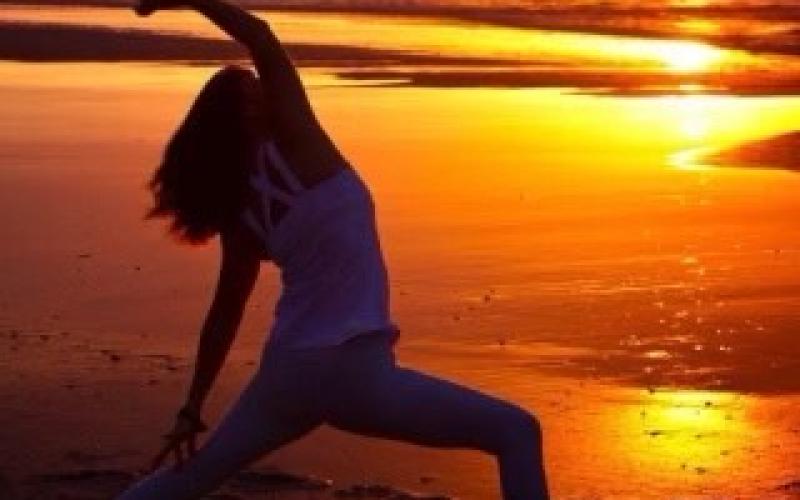 Deb Cunningham in an inverted warrior pose at sunset.
